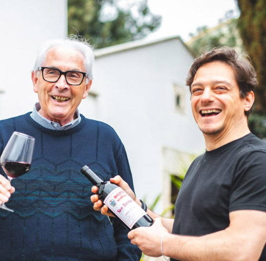 Padre e hijo riendo con una botella de vino